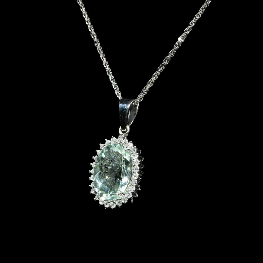 Elegant 18K gold pendant necklace featuring a natural oval-cut aquamarine surrounded by a halo of brilliant natural diamonds suspended from a matching white gold chain.