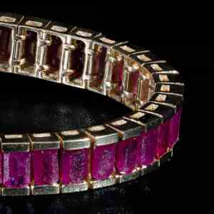 Luxury 18K yellow gold tennis bracelet featuring natural step-cut Burma rubies.