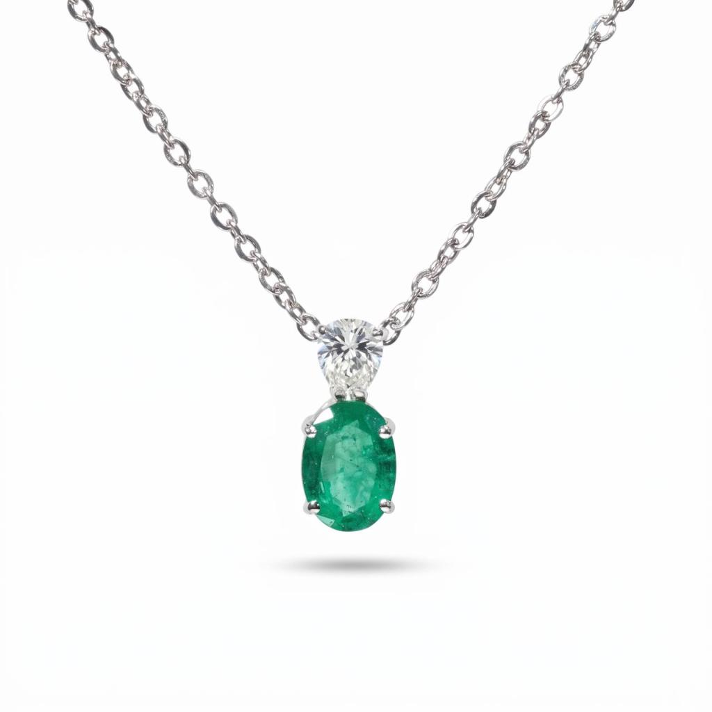 Elegant 18K white gold pendant necklace featuring a natural Colombian emerald with a pear-shaped natural diamond suspended from a matching white gold chain.