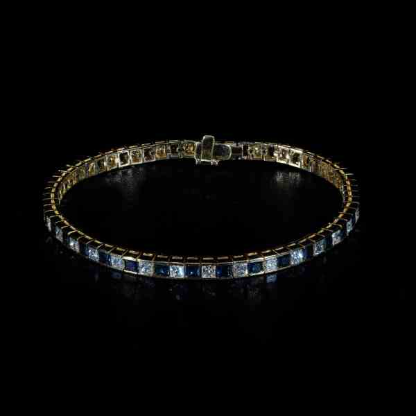 18K yellow gold tennis bracelet featuring alternating natural princess-cut blue sapphires and brilliant-cut diamonds totaling 8.85 carats.