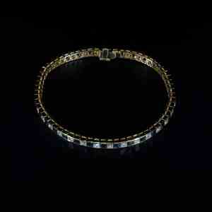 Luxury 18K yellow gold tennis bracelet featuring alternating natural princess-cut blue sapphires and brilliant-cut diamonds.