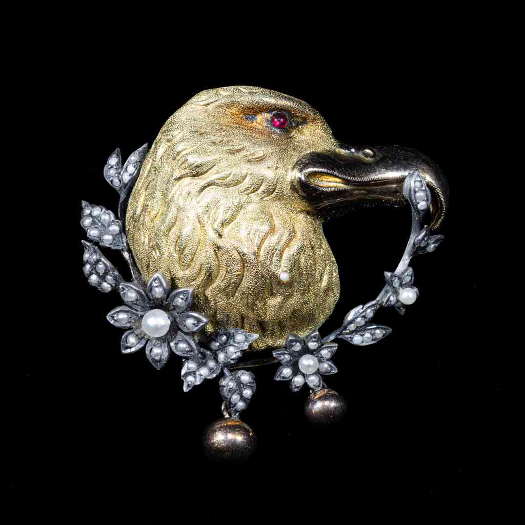 antique gold and silver eagle brooch with natural seed pearls, ruby eye, and intricate floral detailing.