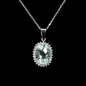 18K white gold pendant necklace featuring a natural oval-cut aquamarine surrounded by a halo of brilliant natural diamonds suspended from a matching white gold chain.
