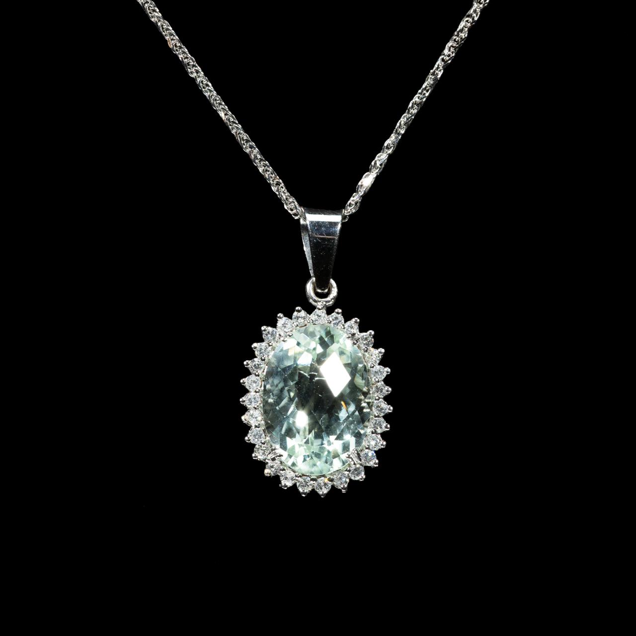 18K white gold pendant necklace featuring a natural oval-cut aquamarine surrounded by a halo of brilliant natural diamonds suspended from a matching white gold chain.