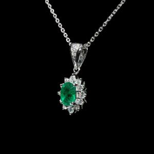 18K white gold pendant necklace featuring a natural Colombian emerald surrounded by a halo of brilliant natural diamonds suspended from a matching white gold chain.