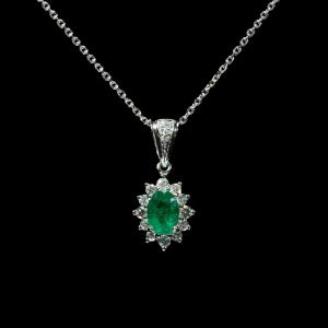 Elegant 18K white gold pendant necklace featuring a natural Colombian emerald surrounded by a halo of brilliant natural diamonds.