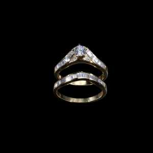 18K yellow gold bridal ring set featuring a 0.35 carat round center diamond and 0.98 carats of baguette-cut diamonds.