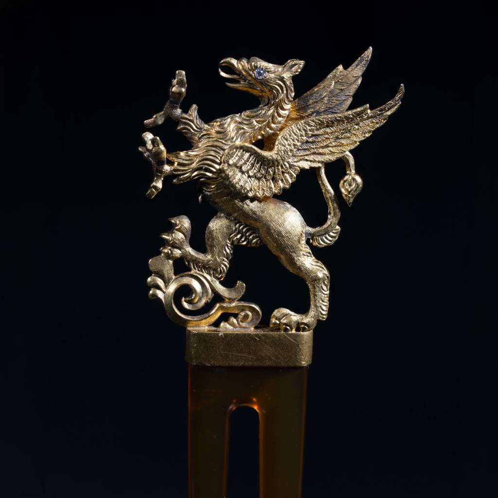 Antique gold winged griffin figural ornament with intricate detailing and jeweled eye