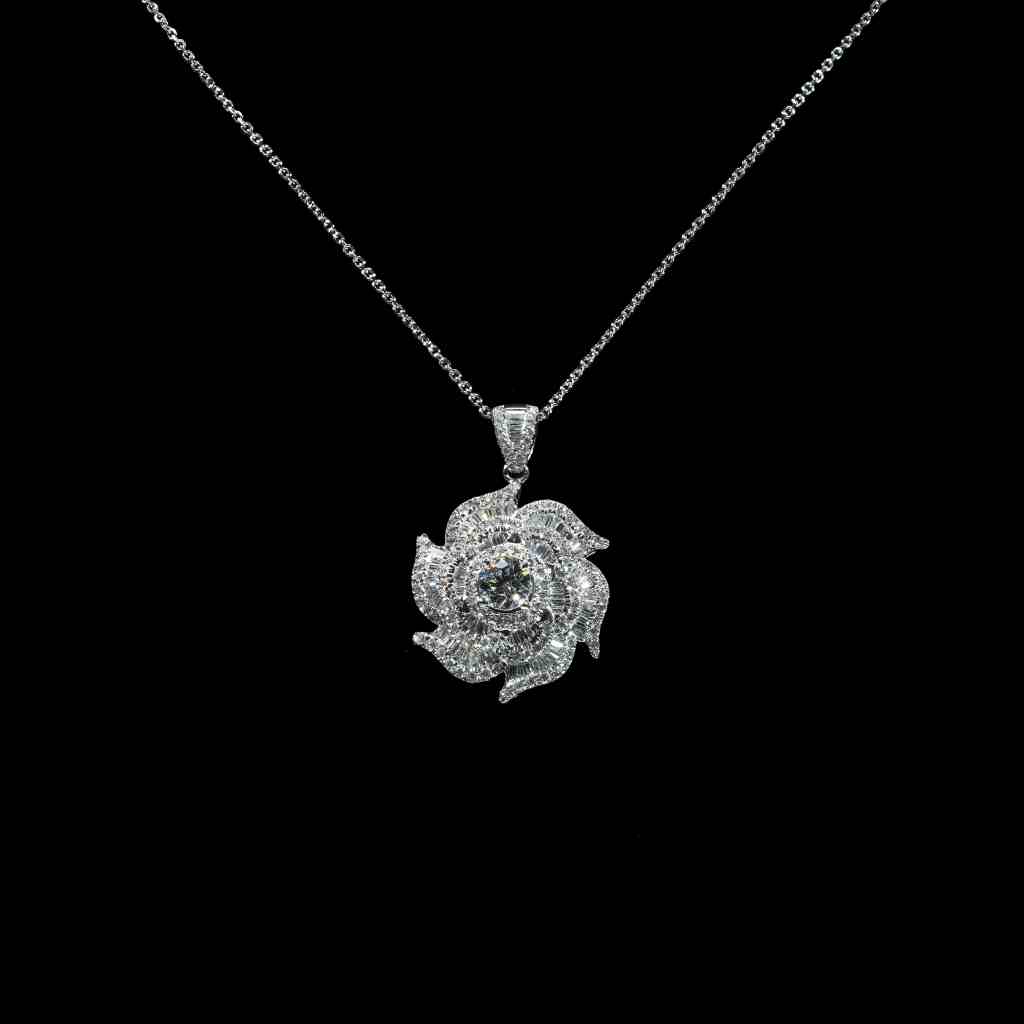 18K white gold floral pendant necklace featuring a 0.60 carat center diamond surrounded by baguette and round brilliant diamonds totaling 2.70 carats.